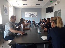 Zdjęcie przedstawia osoby siedzące przy stole na sali konferencyjnej KPP w Kościanie. Są to uczestnicy spotkanie dotyczącego zapewnienia bezpieczeństwa w trakcie wakacji.