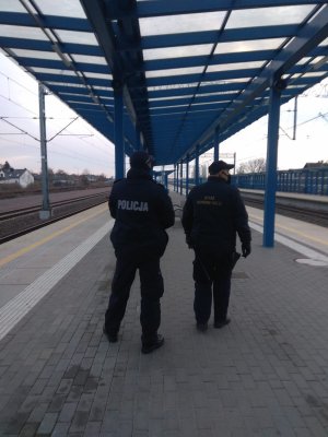 Zdjęcie przedstawia policjanta oraz Strażnika Ochrony Kolei na peronie kolejowym.